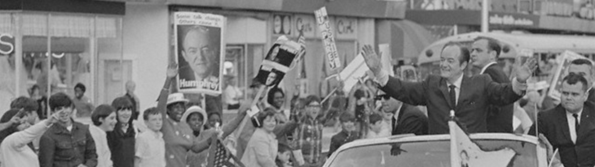 Hubert H. Humphrey rides in a car past people in support of his 1968 presidential campaign