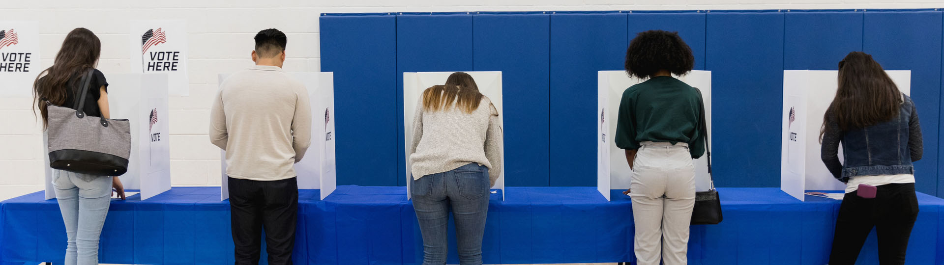 Long shot of several people voting at a polling place
