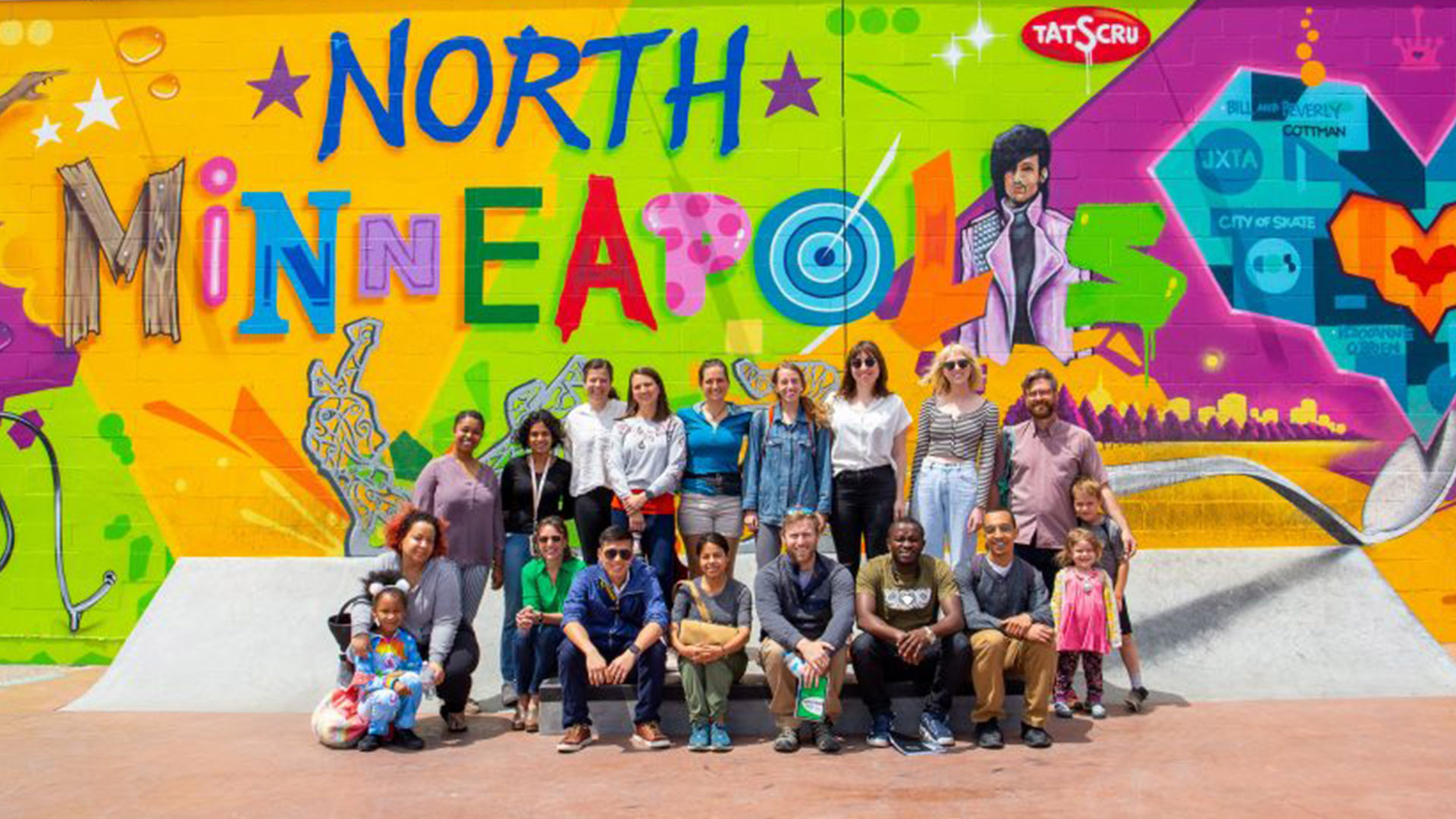 A cohort from the CREATE Initiative poses in front of a colorful mural that says "North Minneapolis"