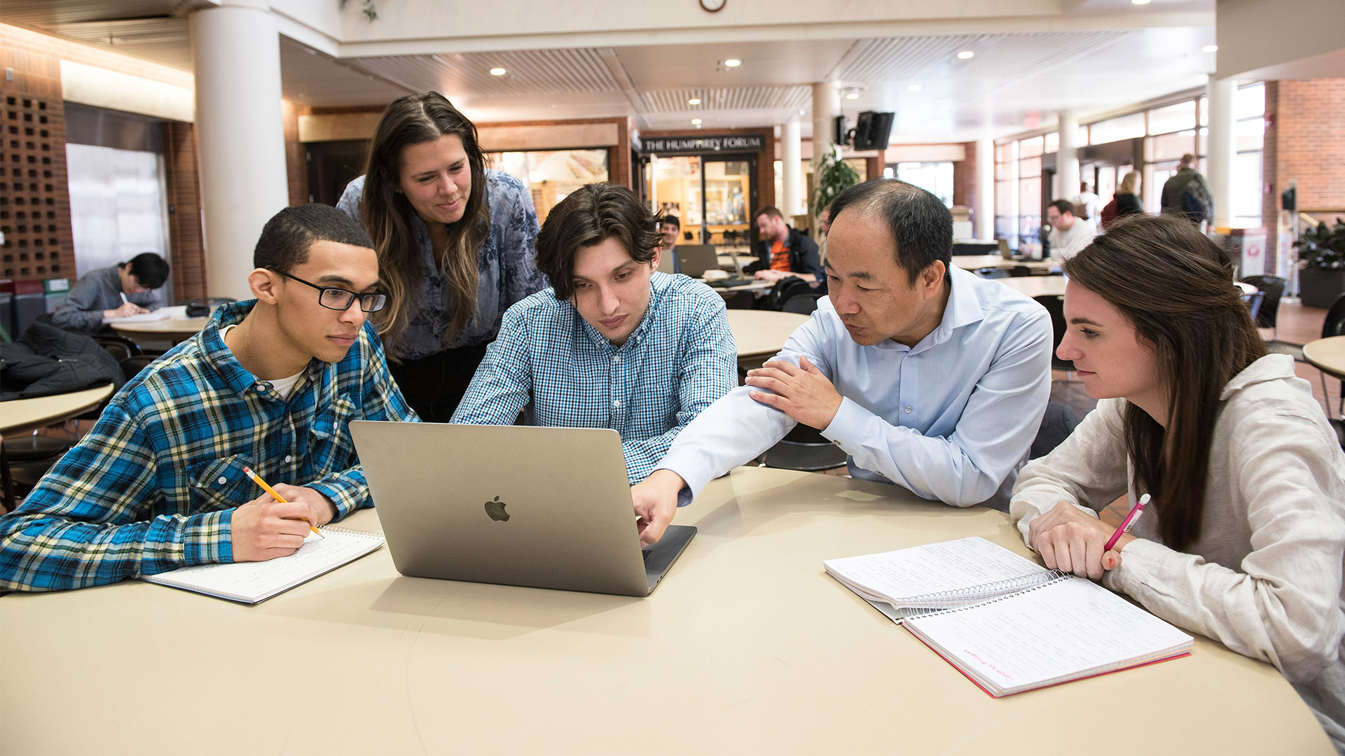 Four students and Professor Jerry Zhao look at a laptop screen