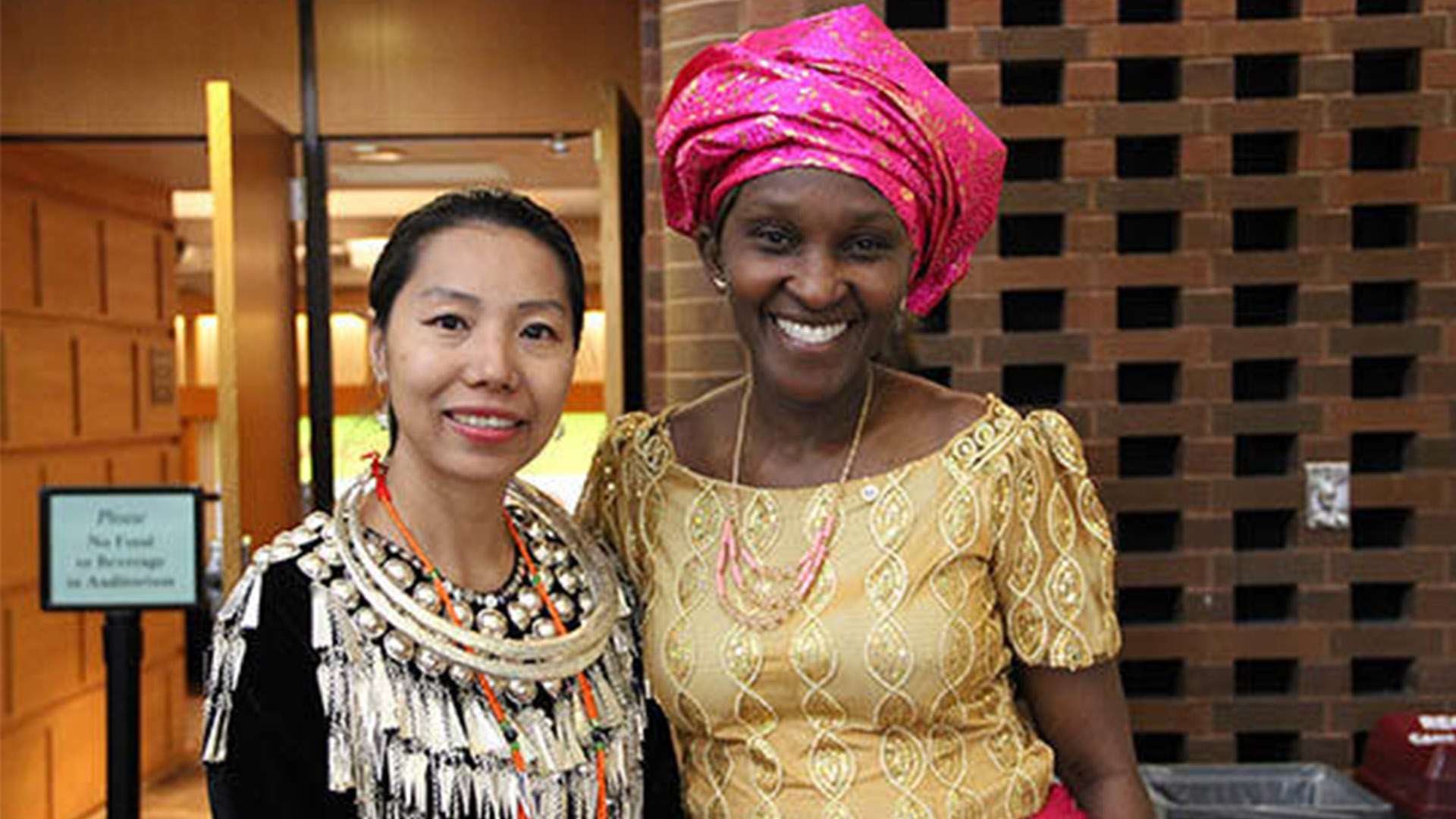 Two Humphrey School International Fellows pose in traditional clothing outside Cowles Auditorium