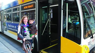 Woman holds a small child standing outside the door of a Metro Transit bus