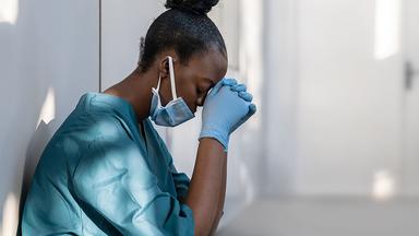 Health care worker leaning against a wall
