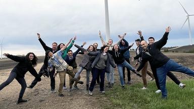 Students pose near a wind turbine