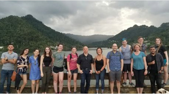 Students and Prof. Gabe Chan in front of a lake and mountains in Puerto Rico