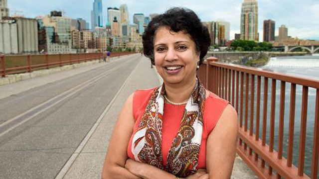 Headshot of Anu Ramaswami on a bridge with the Minneapolis skyline in the background