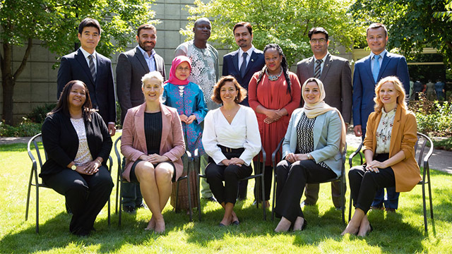 A group of international fellows and scholars sitting on a sunny lawn
