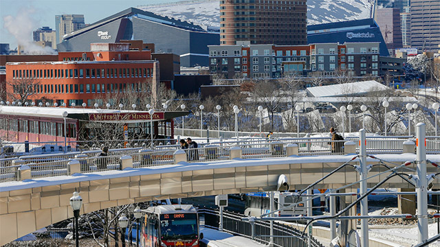The Minneapolis light rail near the University of Minnesota campus, with a bridge and Minneapolis buildings in the background