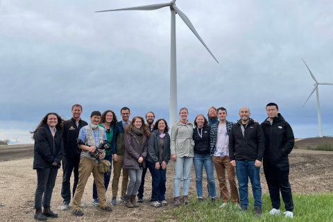 Students and faculty standing in front of wind turbines