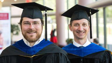PhD recipients Andrew Guthrie and Gregg Colburn in commencement regalia