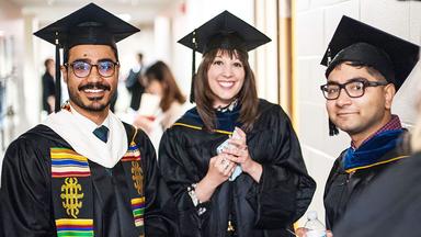 Three Humphrey School graduates at the 2019 commencement ceremony.