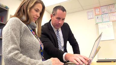 Two teachers at Wayzata High School look at a laptop screen