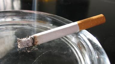 A cigarette rests in an ashtray
