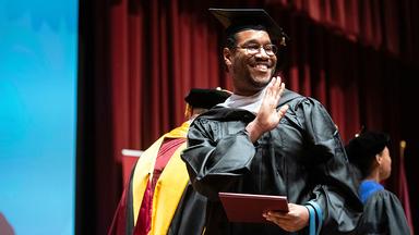 MPA graduate Corey Dawson walks across the stage at 2022 commencement