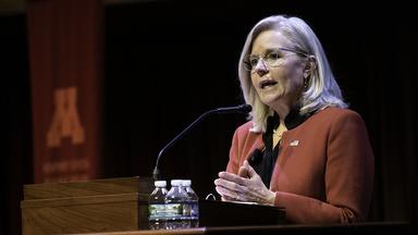 Liz Cheney stands behind a podium and speaks to the audience at Northrop