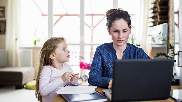 Woman working from home with a young girl next to her