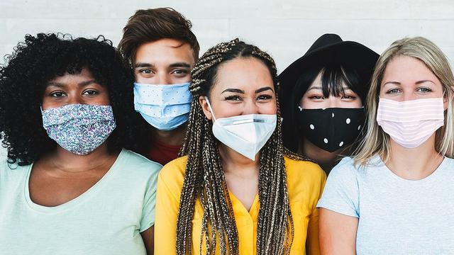 A group of young adults standing together wearing facemasks