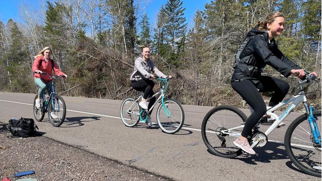 Three people riding bicycles on a paved bike trail