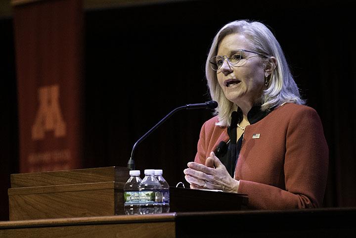 Liz Cheney standing behind a podium speaking to the audience at Northrop