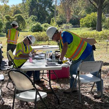 Three government employees conduct soil sampling in a park
