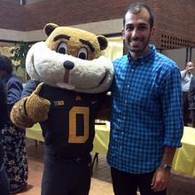 Audel Shokohzadeh stands next to the Goldy Gopher mascot in the Humphrey School atrium