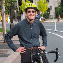 Greg Lindsey sits on a bike, wearing a bicycle helmet